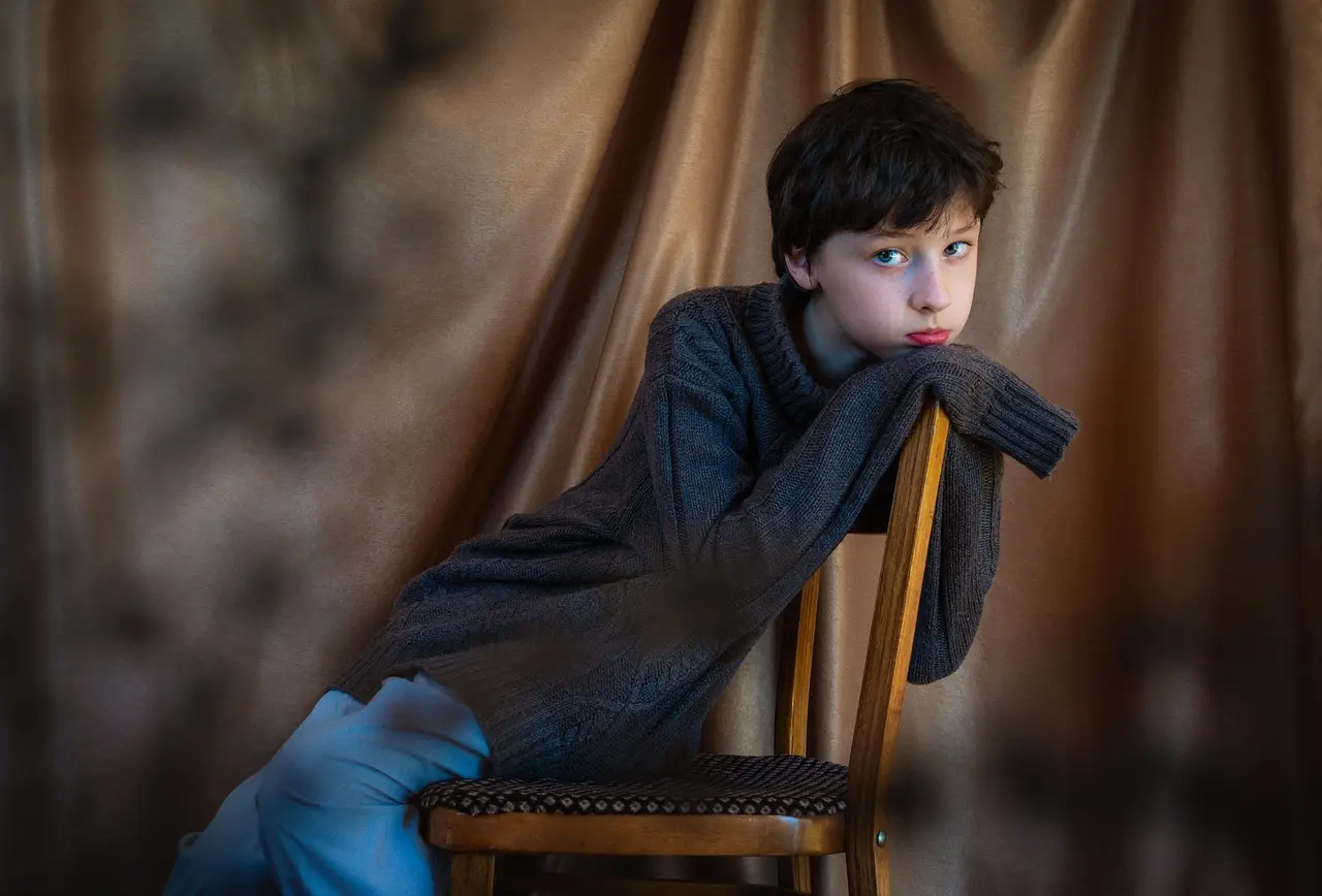 Dreng læner sig over en stol